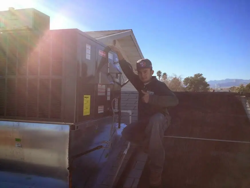 HVAC technician performing Air Duct Cleaning on a rooftop unit in Lexington